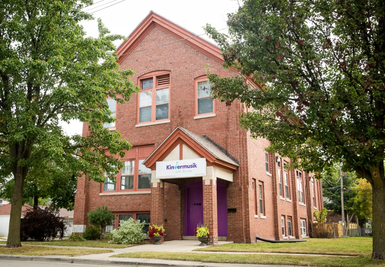 Kenosha Location Harmony Music School's Kenosha location, a red brick building with a Kindermusik with Emilie sign over the purple front door